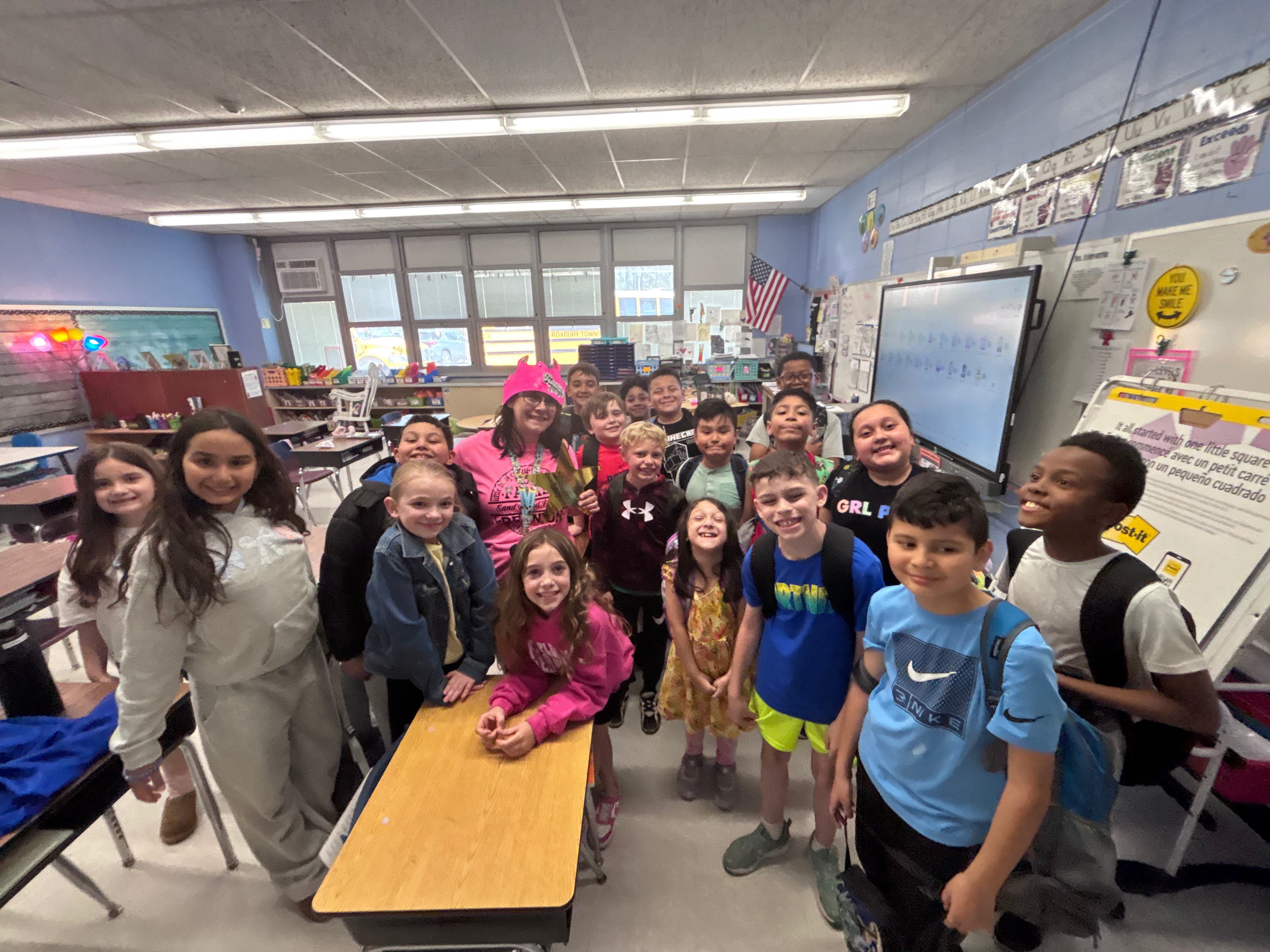 Students gathered around their teacher in a classroom.