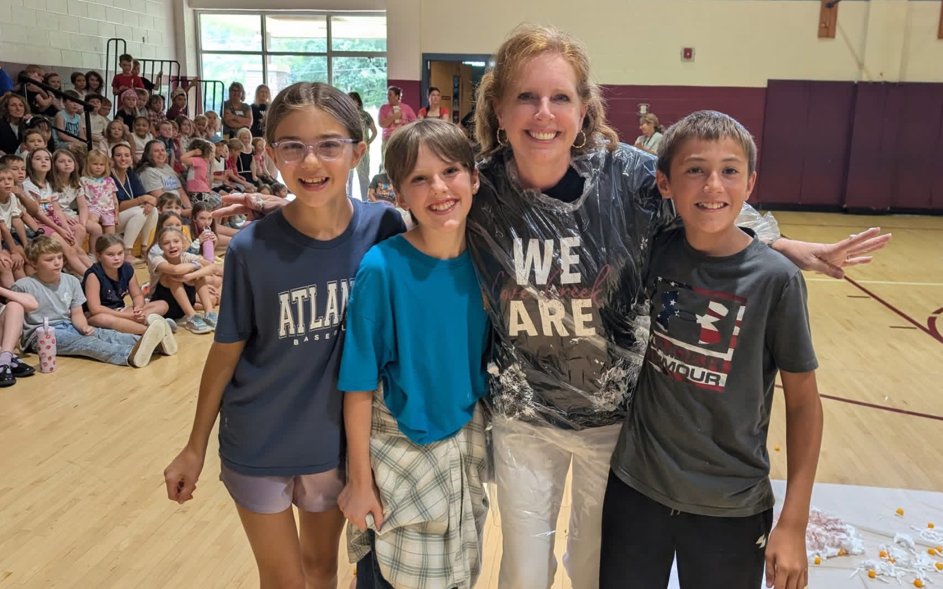 A photo of a teacher with three students smiling at a pep rally.