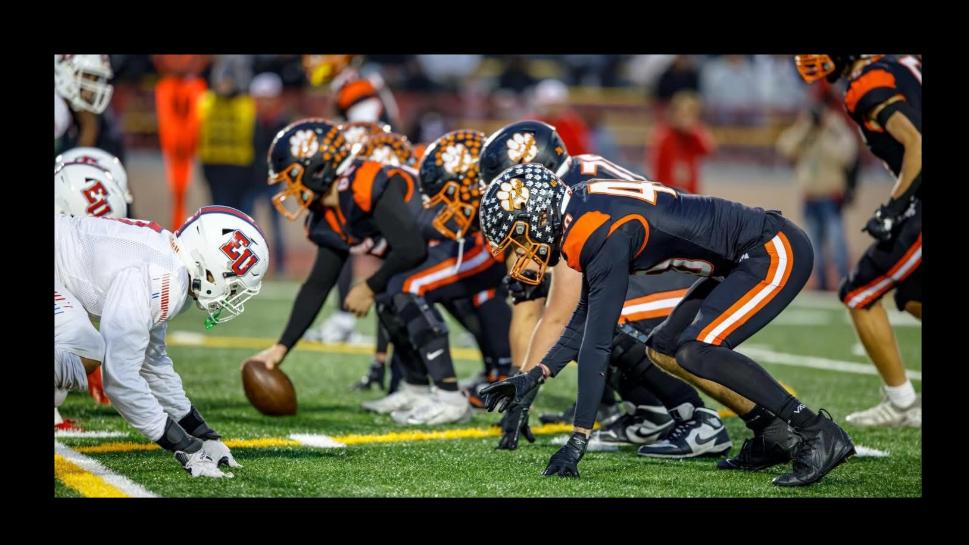 Football game in action with the home team in black and heading for the touchdown.