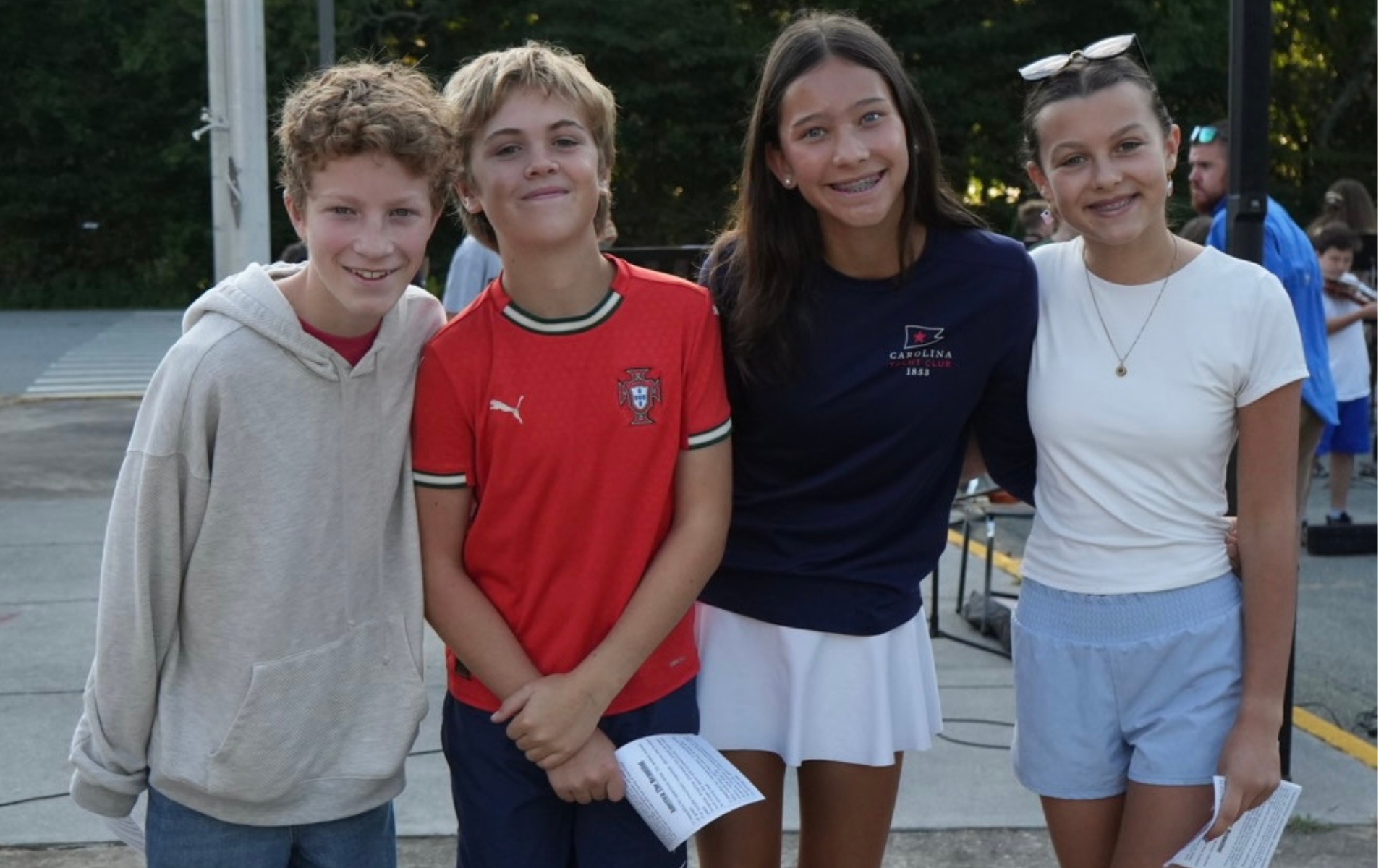 Four middle school students pictured in front of a flag pole before the Patriot Day celebration.