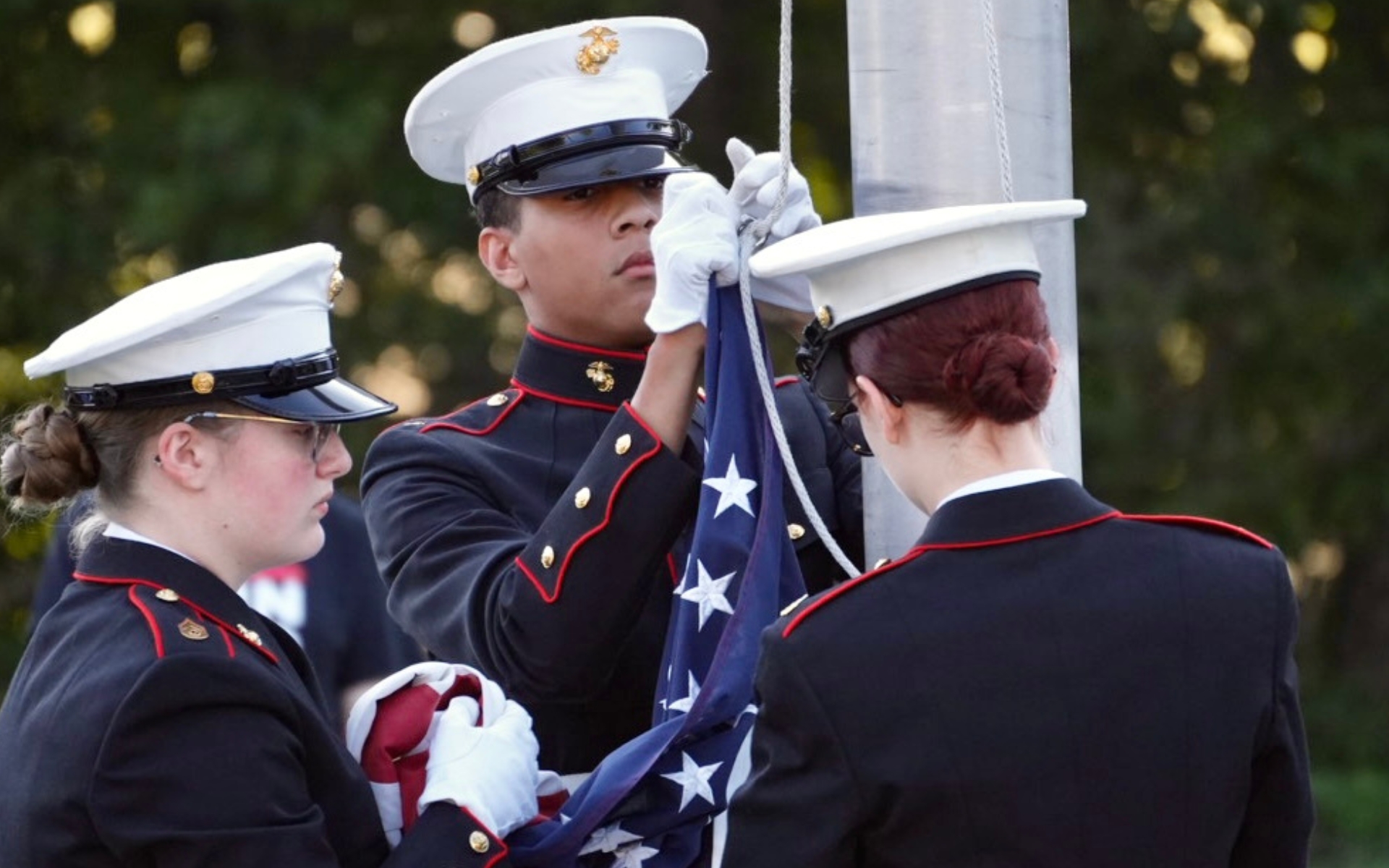 Three high school MJROTC cadets post the colors at the Patriot Day celebration