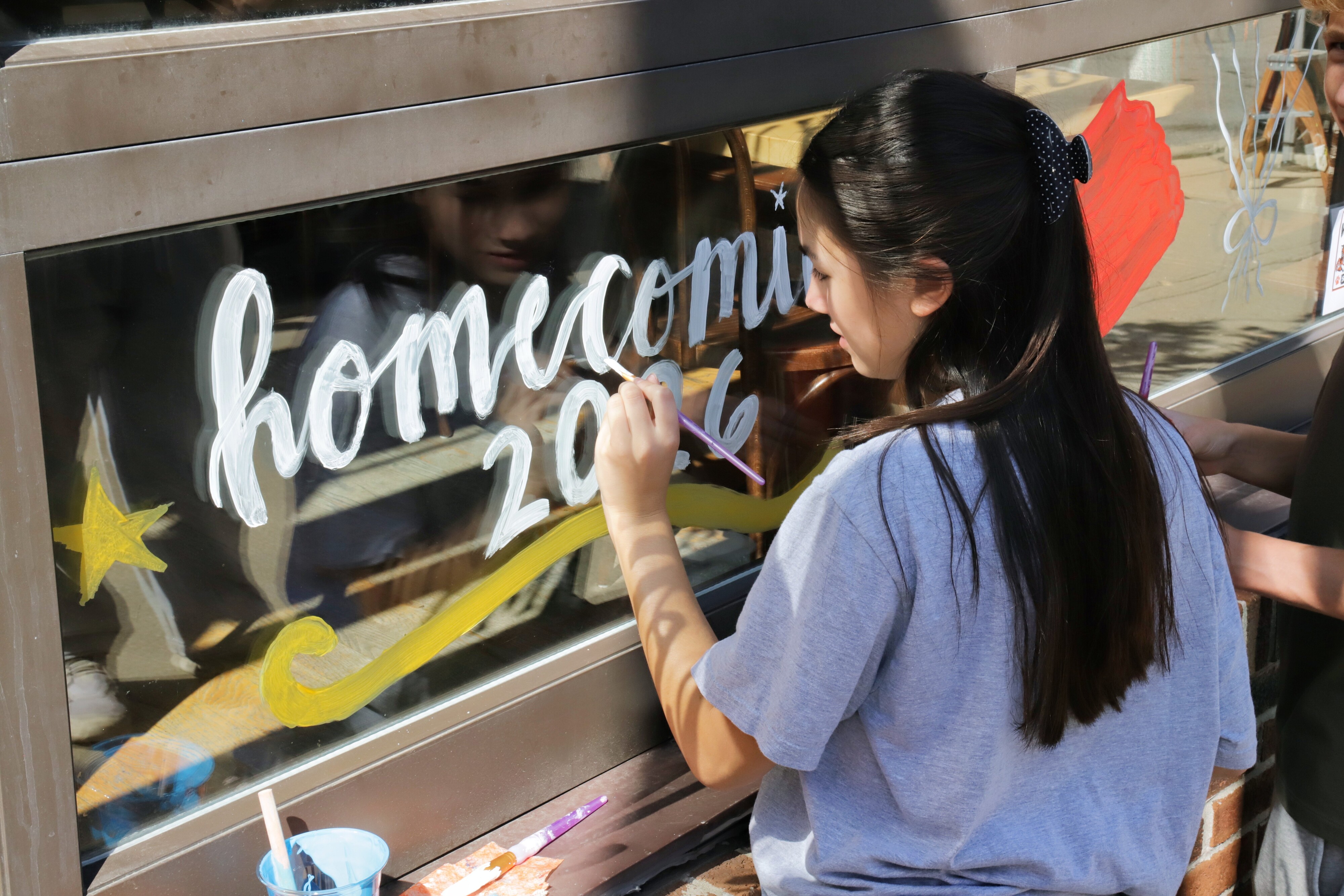 Student Painting a window for homecoming 2026