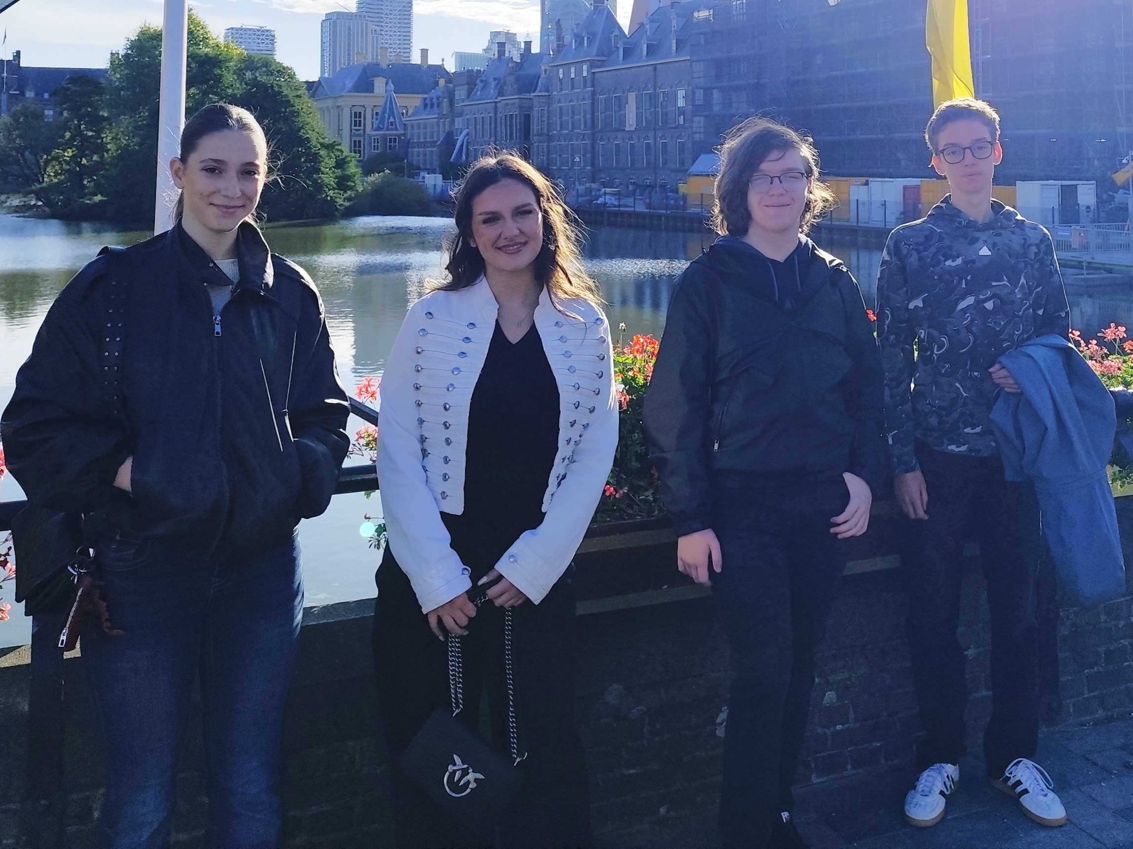 Four NOVA students posing by a lake in front of a historic building