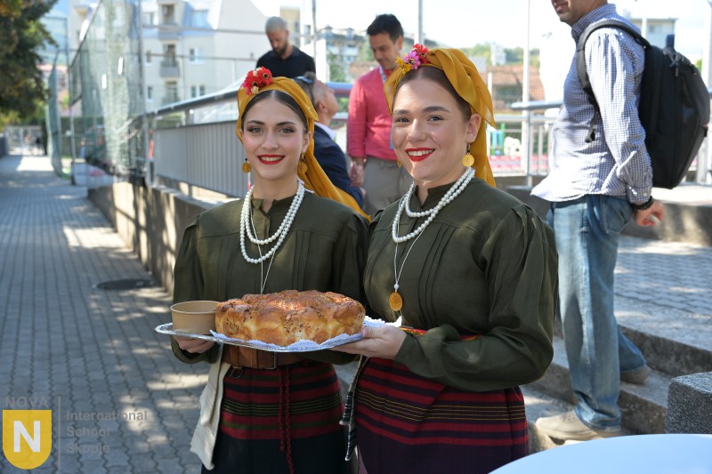 Two women in traditional Macedonian costume holding a tray of bread