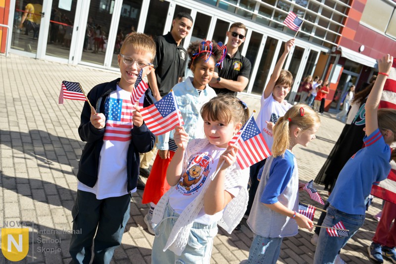 Young students waving American flags outside the school