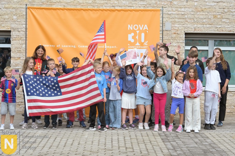Class of students with a large American flag in front of the NOVA 30th anniversary banner