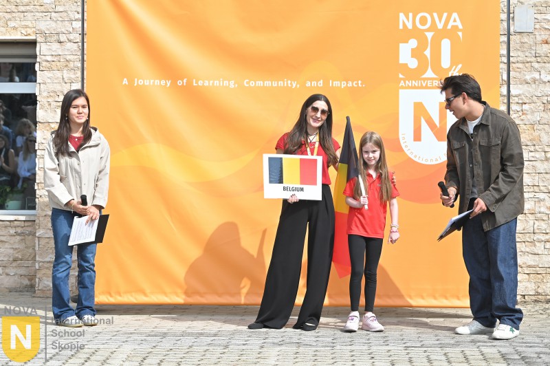 Parent and child holding the Belgian flag and sign at the Parade of Nations