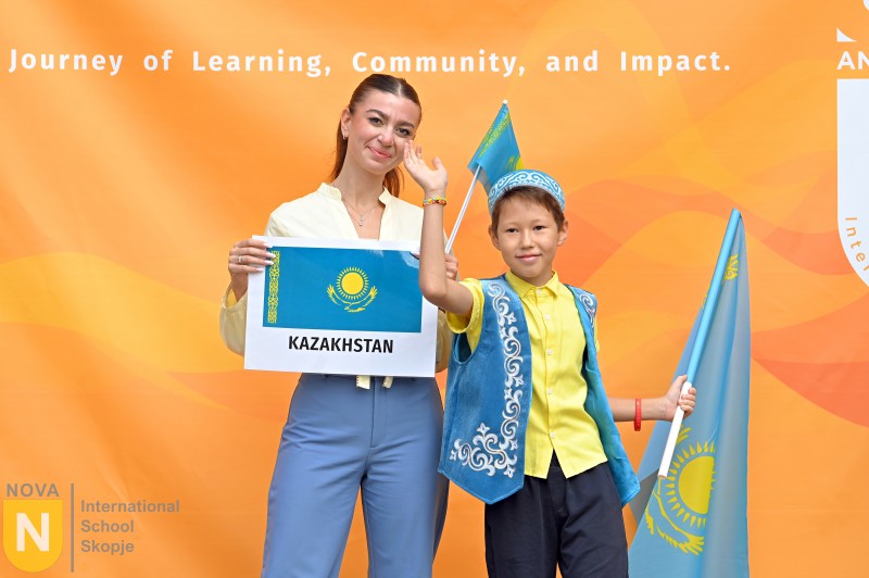 Student in traditional dress holding a Kazakhstan sign and flag