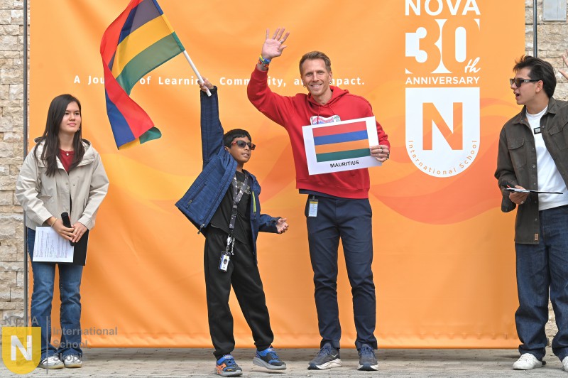 Parent and child waving their flag and country sign at the Parade of Nations