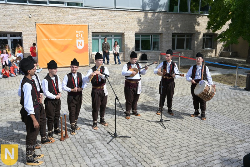 Folk ensemble performing in front of the school building