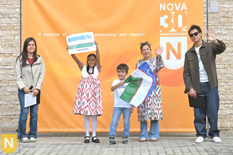 Young students holding flags in front of the NOVA 30th anniversary banner