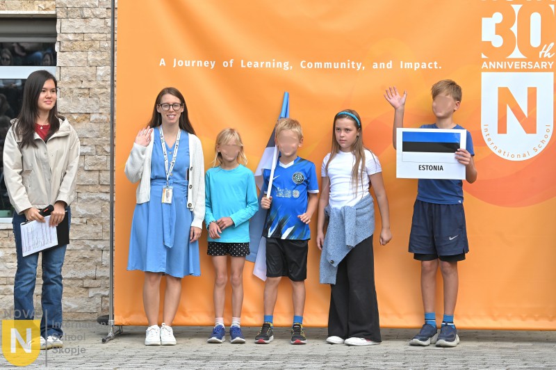 Young students holding a country sign in front of the NOVA 30th anniversary banner