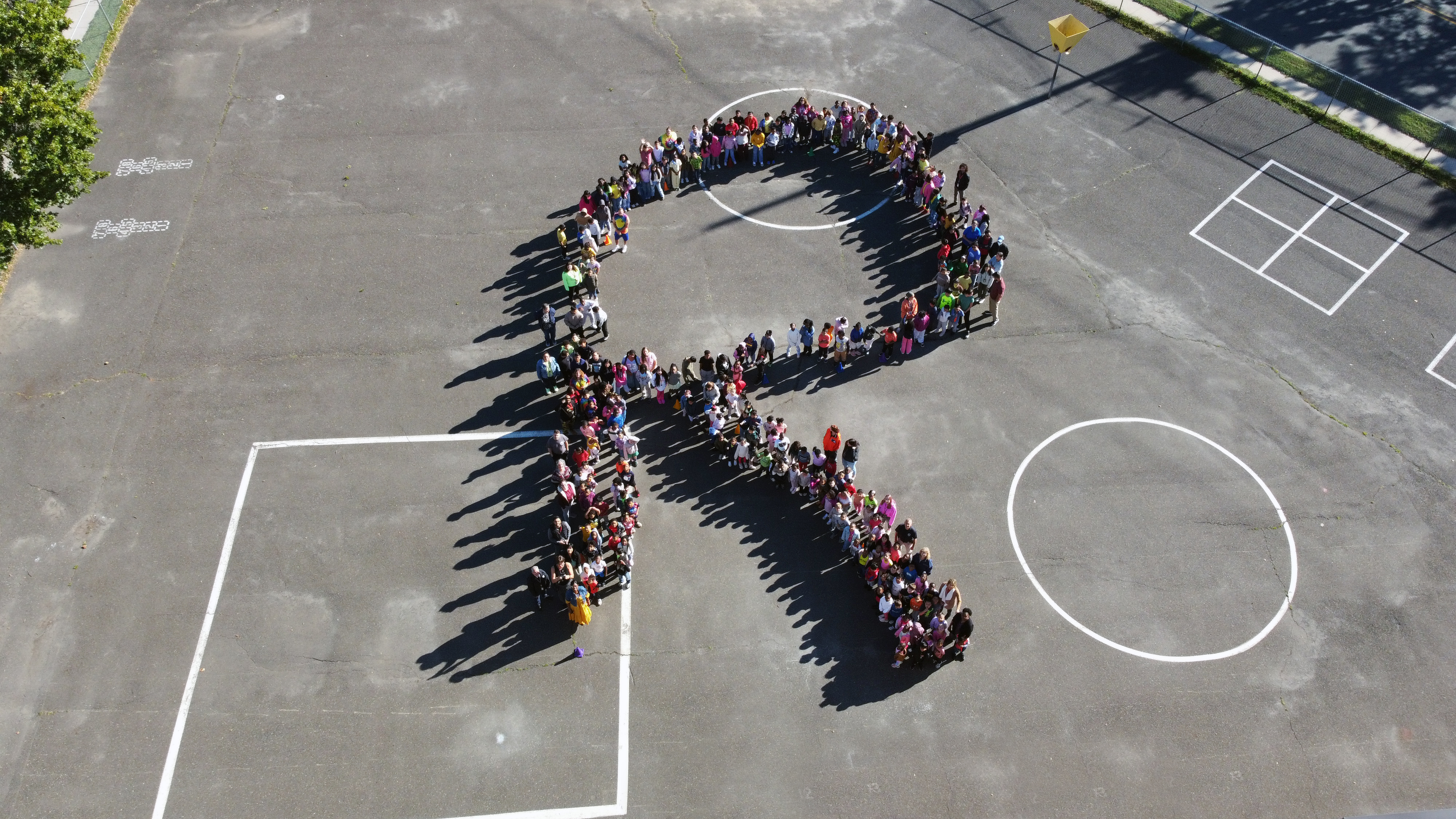 Students on a blacktop spelling out the letter R